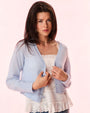 A brunette woman holding open a blue cardigan paired with a white lace top, standing in front of a white background.