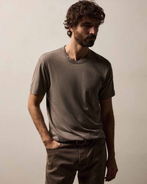  A man wearing a Brushed Lotus Crew t-shirt and pants stands casually.