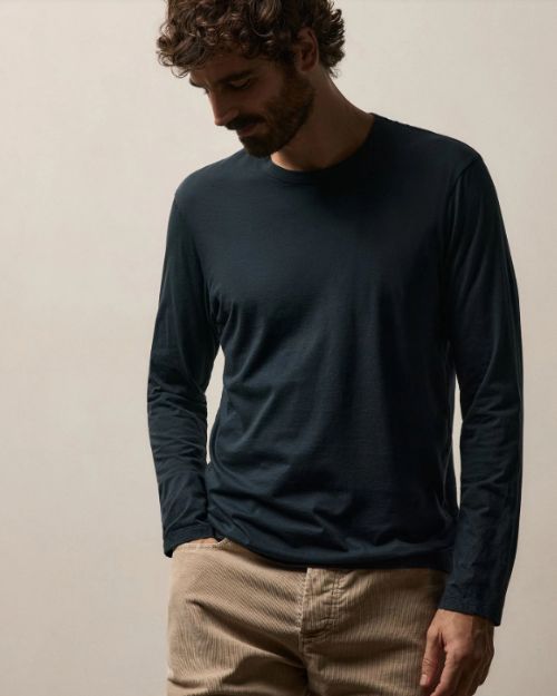 A man wearing a French Navy long sleeve crew shirt and khaki pants stands confidently.