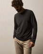 A man in a long sleeve shirt and khaki pants stands, showcasing a relaxed and stylish look.