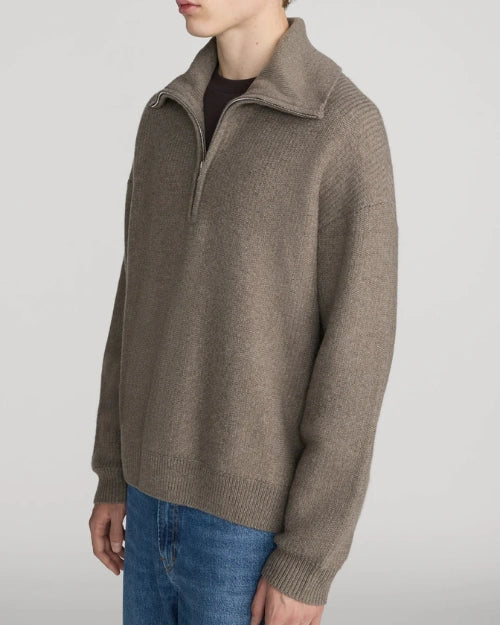 Taupe zip-neck knit sweater featuring a high collar, long sleeves, and a relaxed fit, styled with blue denim jeans on a light grey background.