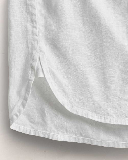 Close-up view of the bottom of a white long sleeve linen shirt.
