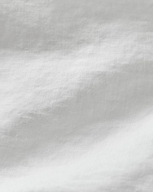 Close-up view showing detail of a white linen long sleeve shirt.