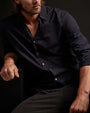 A man with long hair wearing a cotton button-up shirt.