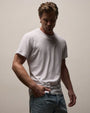White crew neck T-shirt featuring a classic short-sleeve design and relaxed fit, styled with light wash denim jeans on a neutral studio background.
