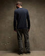 The back view of man in a long sleeve crew neck cotton shirt posing against a wall.