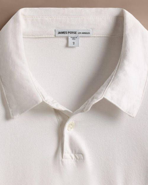 A 100% white cotton rugby shirt with a white collar, highlighting its minimalist and elegant style.