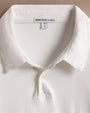 A 100% white cotton rugby shirt with a white collar, highlighting its minimalist and elegant style.