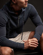 A man in a vintage French zip-up hoodie and shorts sits on a bench, looking relaxed.