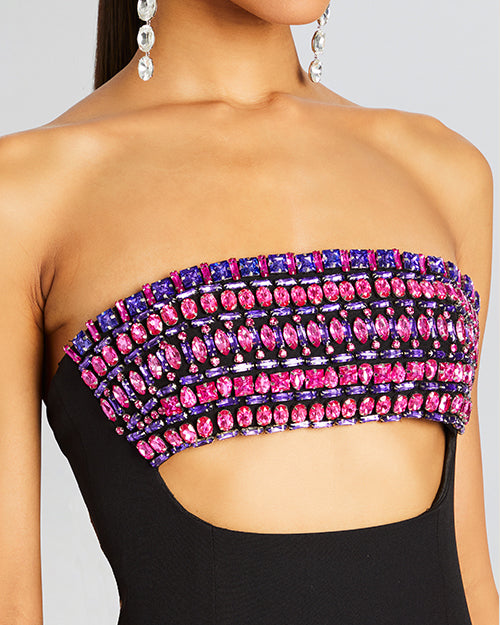 A  dress with a black bodice with a cut-out detail around the waist and a purple sequined pattern on the bust area. The bust area has purple and pink rhinestones for a shiny effect. 