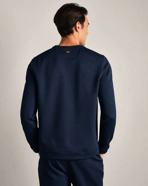 Back view of a navy long-sleeve performance crewneck shirt with textured fabric and athletic fit, paired with matching navy pants.