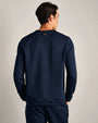 Back view of a navy long-sleeve performance crewneck shirt with textured fabric and athletic fit, paired with matching navy pants.