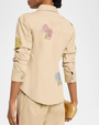 Woman wearing a khaki jacket with embellished flowers on a white background. 