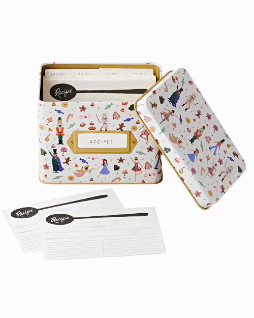 Decorative tin recipe box with whimsical patterns, featuring dancers and holiday motifs. Includes recipe cards and dividers labeled for organization.