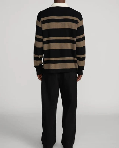 Back view of a long-sleeve rugby-style knit polo sweater with black and brown horizontal stripes and a contrasting cream collar, paired with black wide-leg trousers.