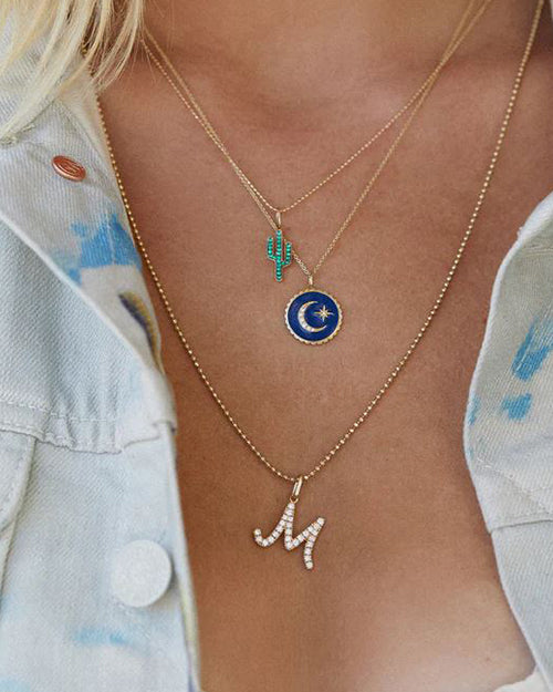 M initial in pave diamonds with a ball chain necklace.