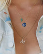 M initial in pave diamonds with a ball chain necklace.