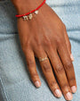 Hand model showing Love script ring in yellow gold and pave diamonds, and a beaded bracelet with 3 sydney evan charms.
