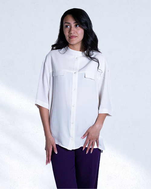 Brunette model wearing Silk Crepe Shirt in white with purple pants in front of white background.