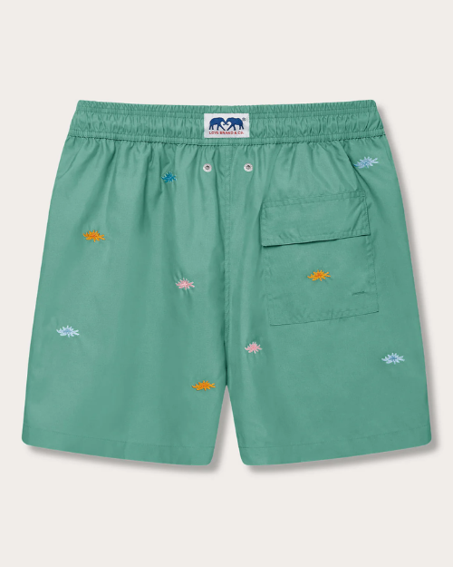 A green pair of shorts with a pocket on the left with orange and blue embroidered suns. 