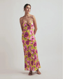 Woman with a yellow dress with pink flowers against a grey background.