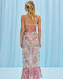 Back view of a woman wearing a fitted tropical print bikini top with flutter straps and a clasp closure, highlighting its design and a cover up tropical print skirt.