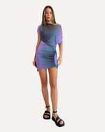 Woman wearing a gradient purple and blue dress with chunky black sandals on a white background 