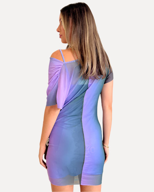 Back view of a woman wearing a pastel gradient purple and blue dress against a white wall