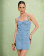 A woman in a denim mini dress by PATBO, embellished with gold buttons on the straps for a chic look.