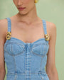  woman showcases the PATBO Marina Denim Mini Dress, characterized by its denim fabric and decorative gold buttons.