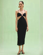 A woman displays the PATBO Frida Mesh Midi Dress, characterized by its chic black color and fashionable cutouts.