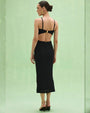 Woman's back view in a black PATBO Frida Mesh Midi Dress, highlighting the dress's stylish mesh details and fit.