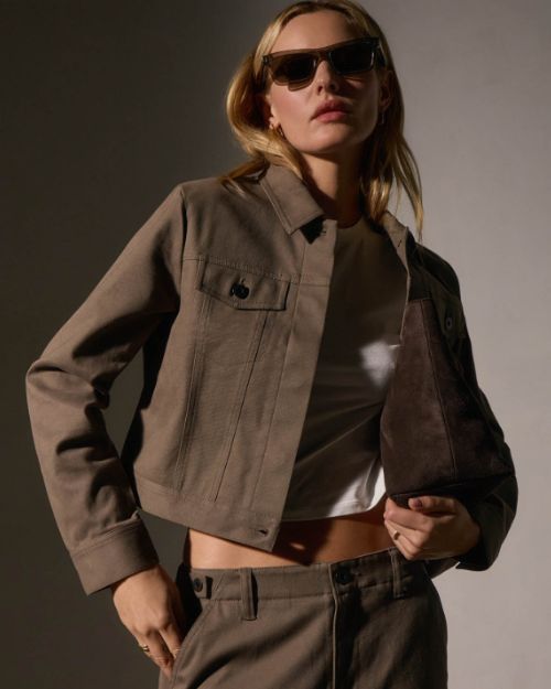 A model poses in a stylish cashmere jacket and matching pants, showcasing a modern, casual outfit.
