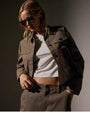 A woman dressed in a white shirt and cashmere jacket with matching pants, embodying a stylish and relaxed appearance.