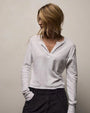 A woman wearing a long sleeve white cotton shirt and black pants stands confidently.