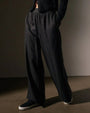 A woman in lightweight black linen pants and a sweater stands confidently, showcasing a casual yet stylish outfit.