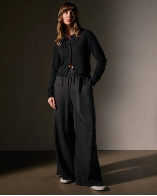  A model wearing a black sweater paired with lightweight linen wide-legged black pants.