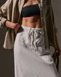 A  model wearing a black top and a high-low white linen skirt.
