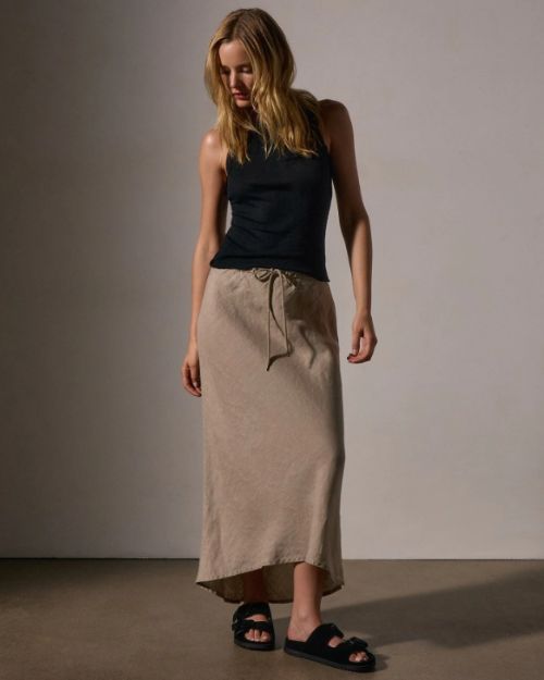 A model in a black tank top paired with a high-low linen skirt.