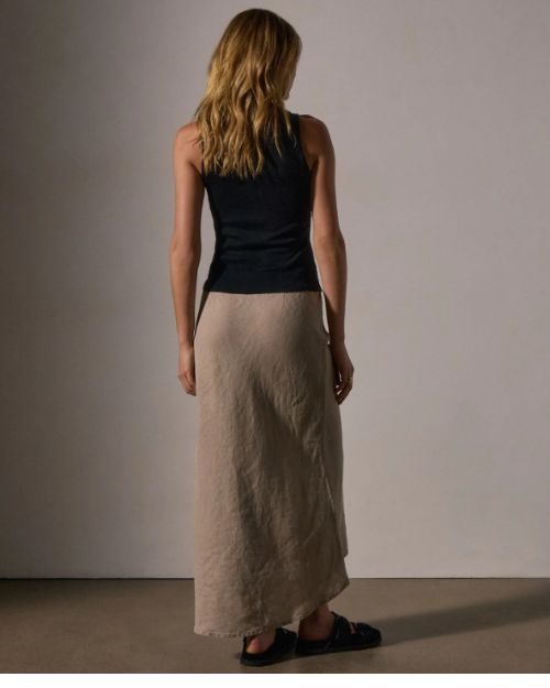 The back view of a model wearing a black top and a high-low skirt made of linen.