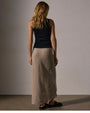 The back view of a model wearing a black top and a high-low skirt made of linen.
