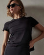 A model wearing a black crop tee shirt and sunglasses, showcasing a stylish summer look.