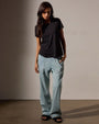 A model showcases a ladies' black crop tee shirt paired with blue denim pants.