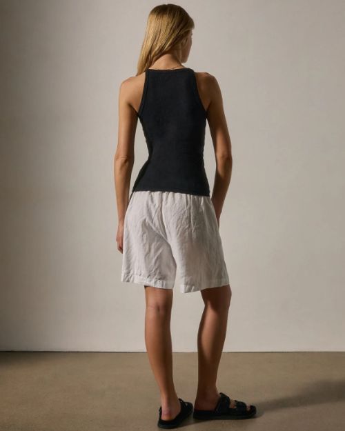 Woman's back view wearing a 100% cotton tank top and shorts, showcasing a relaxed summer outfit.