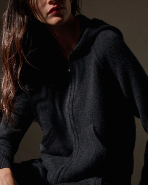  A woman dressed in a black cashmere track jacket and matching pants, showcasing a stylish and casual look.