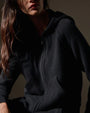  A woman dressed in a black cashmere track jacket and matching pants, showcasing a stylish and casual look.