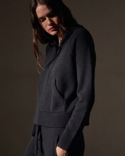 The model is dressed in a black cashmere sweatshirt and sweatpants, presenting a chic and casual look.
