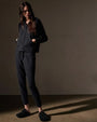 A model wearing a black cashmere track jacket and slippers, showcasing a casual and comfortable outfit.