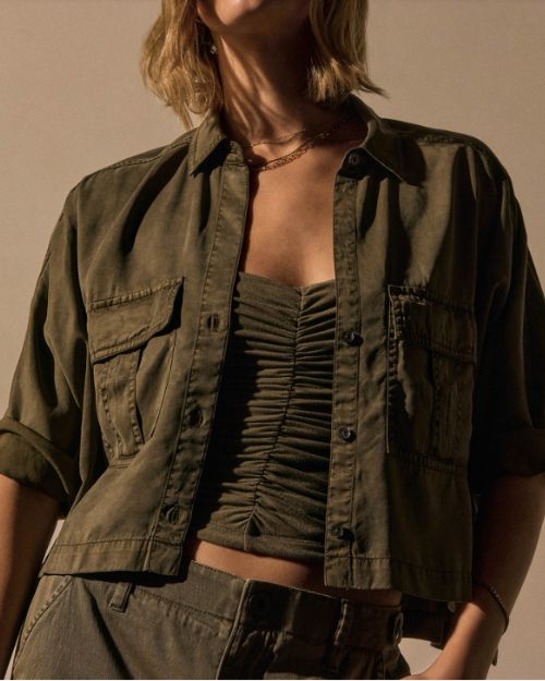 A woman wearing a Birch pocket cropped shirt and matching pants stands confidently, showcasing her outfit.