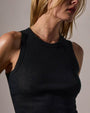 Model wearing a fitted black tank top made of soft, lightweight cotton cashmere rib with raw hem and jersey binding details.